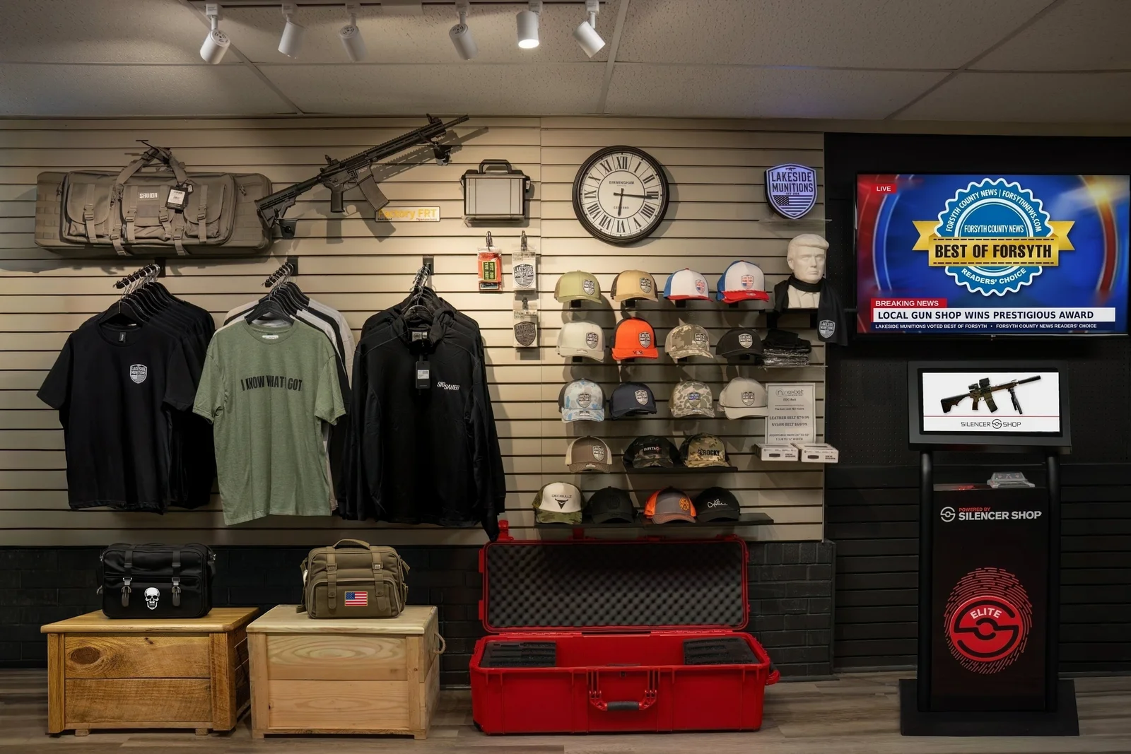 Lakeside Munitions shirts, caps and hoodies on a slatwall beside a Silencer Shop Elite kiosk
