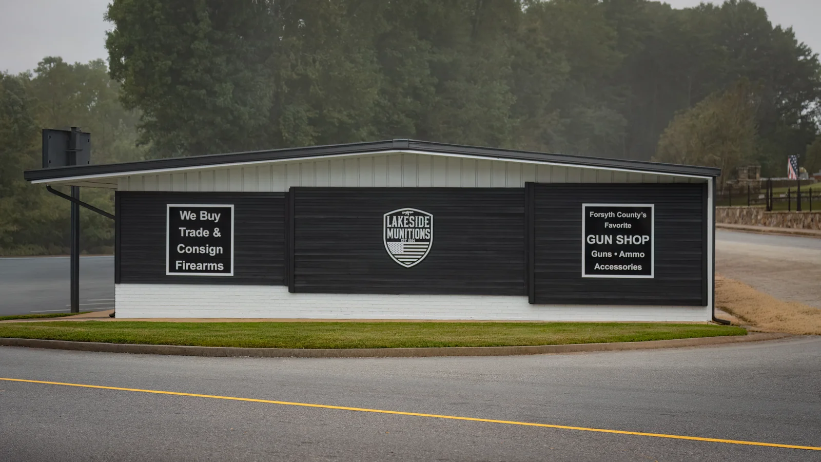 Side wall of the gun shop with We Buy Trade and Consign Firearms signs and a Lakeside shield