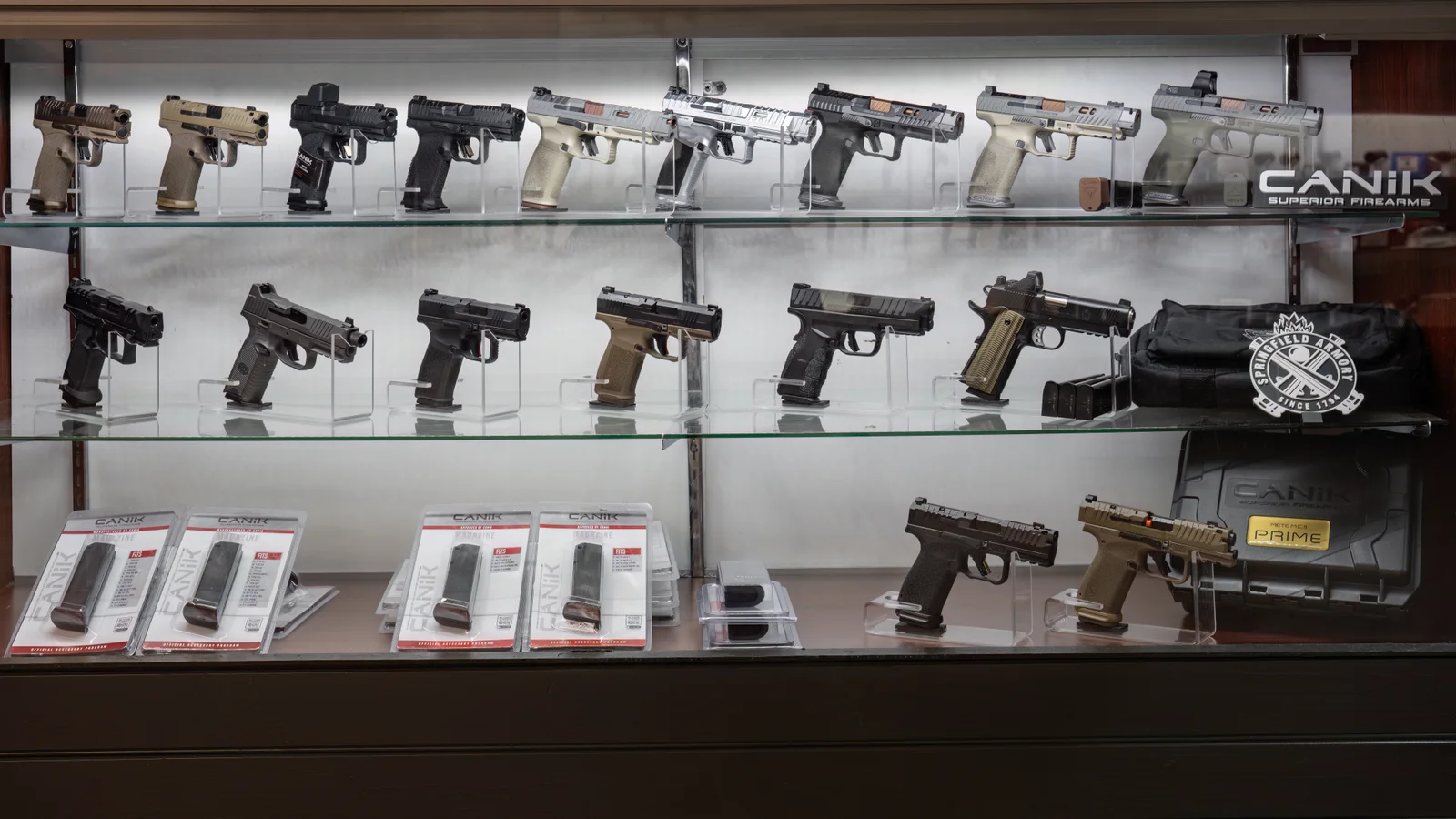 Glass case of pistols on three shelves, with magazines on the bottom
