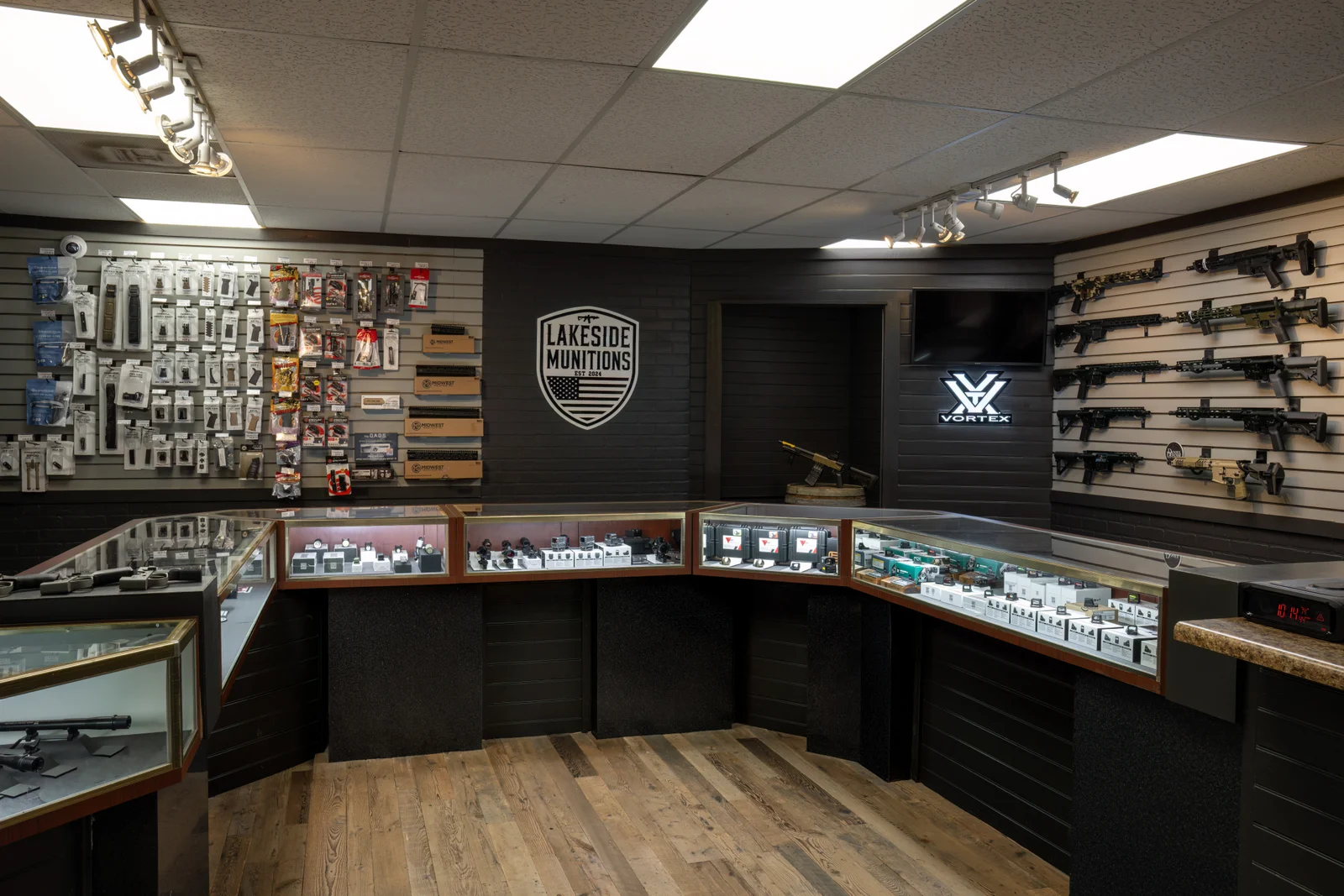 Optics counter with red dot sight boxes in glass cases, a lit Vortex sign and a Lakeside shield